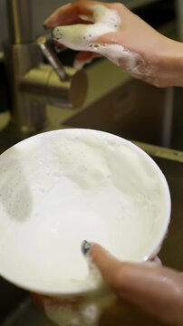 Close Up of Asian Woman Hands Washing White Bowl in Kitchen Sink