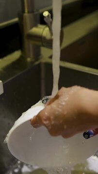 Close Up of Asian Woman Washing White Bowl in Kitchen Sink