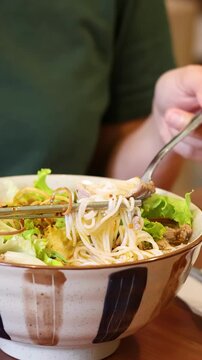 Vietnamese Person Eating Bun Cha Noodles with Chopsticks in Restaurant