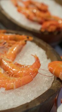 Person Using Tongs to Pick Fresh Cooked Prawns from Ice