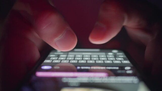 Mobile phone texting shown by male hands typing message on touchscreen keyboard in close up at night. Mobile phone usage reflects digital communication habits social media messaging, online lifestyle
