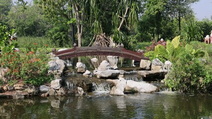 Obraz premium Small Wooden Bridge Over a Cascading Waterfall in a Lush Garden