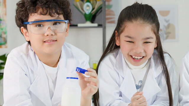 Asian boy and girl in lab coats conducting a science experiment