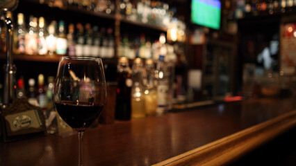 Close-up of a Red Wine Glass on a Polished Wooden Bar Counter © blueringmedia