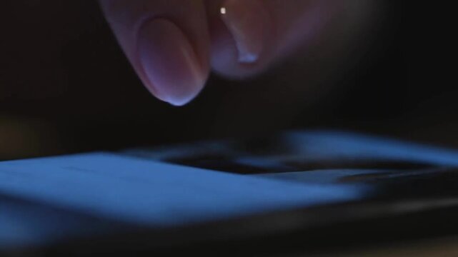 Close-up macro shot of person using smartphone browsing pictures on social network Male finger scrolling social media app feed in dark background