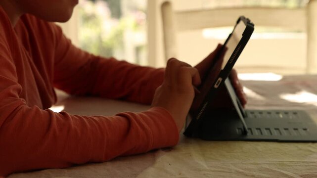 12 year old boy using tablet computer at home at sunset