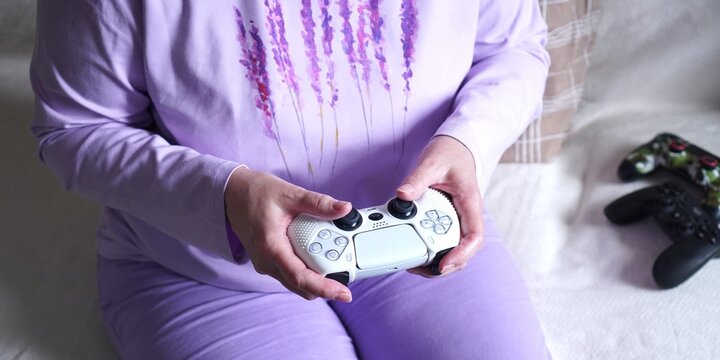  Georgia, March 23, 2025: A person dressed in purple loungewear holds a game controller, ready to engage in a gaming session. The setting is relaxed and cozy, emphasizing personal entertainment.