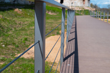 Fototapeta premium A clean, metal railing lines a walkway surrounded by green grass on a bright, sunny day.