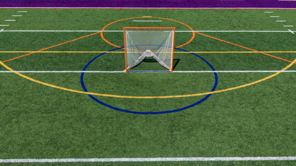 Aerial view of a multi-purpose athletic turf field featuring a lacrosse goal within a blue circular crease and overlapping colored lines for different sports.  Lacrosse, Soccer, Field Hockey, Football © Thomas