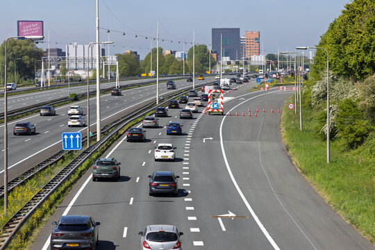 Utrecht, Netherlands, April 25, 2026 - Traffic merging on the A12 highway during roadworks with a mobile warning trailer and traffic cones for safety.