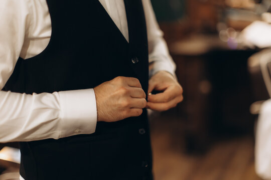 Groom getting ready buttoning up his suit vest