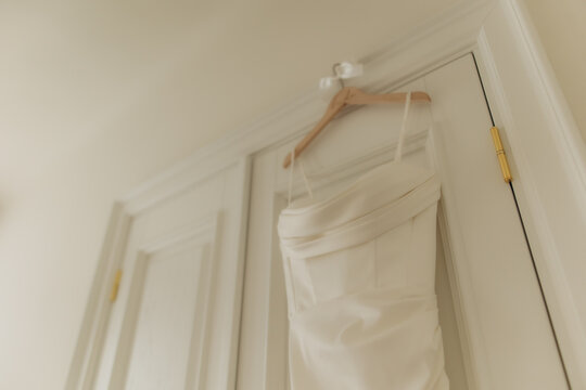 Wedding dress hanging on a door, bride getting ready