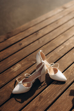 White bride shoes resting on wooden deck