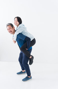 おんぶするスポーツウェアを着たミドル夫婦