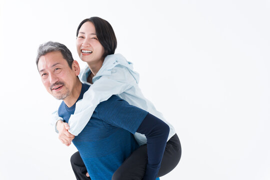 おんぶするスポーツウェアを着たミドル夫婦