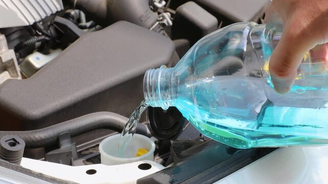 自動車のボンネットを開けてウィンドウォッシャー液を補充している