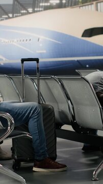 Vertical video Jet lagged passengers sleeping in airport during air transport congestion causing delayed flights. Multiethnic people napping on chairs in lounge during holiday trip, waiting for