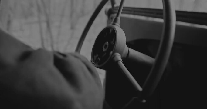 Hands of a military driver holding an old car steering wheel