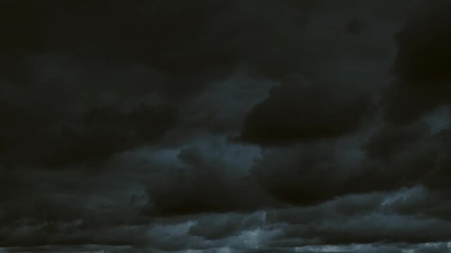 timelapse, time lapse heavy, pitch-black storm clouds covering the entire sky. A brooding and dramatic atmospheric background representing horror or bad weather.