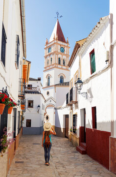 female traveler in narrow street looking at church of incarnation in arriate spain, Malaga province