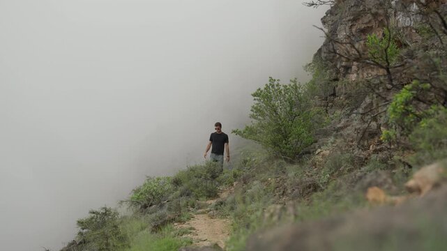 Static Shot of Tourist at Jebel Samhan Overlook, Cinematic Male Traveler Above Rolling Clouds and Fog in Salalah Oman