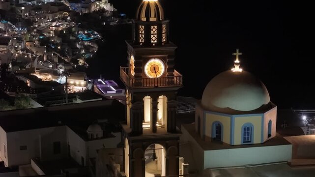 A drone orbit around a traditional church belfry, using the parallax effect to reveal the sprawling golden lights of Fira village perched along the dark caldera cliffs.