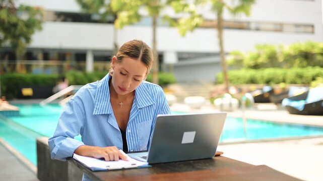 Woman typing on laptop working remotely outdoors. Digital nomad lifestyle, online business, productivity, freelance work, modern workspace