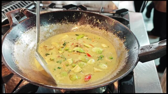 Spicy and creamy chicken green curry in a pot, popular Asian cuisine.