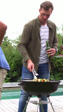 Vertical video: Turning cook in olive top tending kettle serving kebab on deck as red tee coming