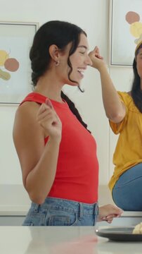 Vertical video: Flicking woman on island urging pal clapping, swaying at kitchen, dessert playful