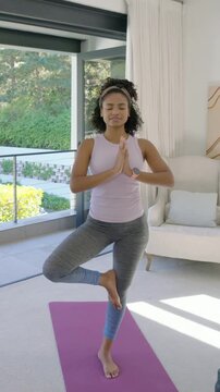 Vertical video: Lowering foot, woman in purple top stepping to lunge on purple-mat at home for calm