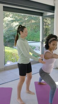 Vertical video: Entering coach in green top adjusting client squat on purple mat in gym for form
