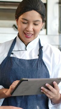 Vertical video: Tapping tablet, chef reading recipe and checking steps in kitchen, denim apron