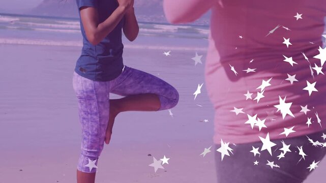 Two women doing yoga, balancing tree pose on pink mat, second moving from right, sparkles obscuring