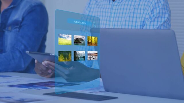 Center member tapping tablet, activating blue hologram panel loading tiles beside laptop for design