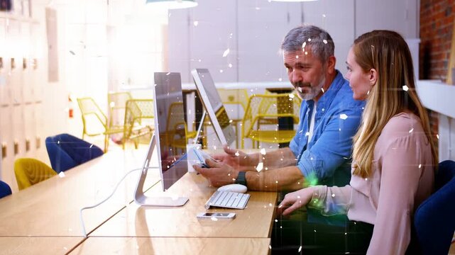 Man using device, woman pointing at monitor for tech training, bokeh overlay floating over monitor
