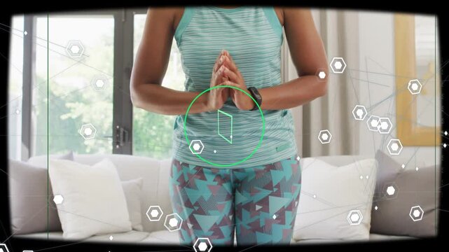 Woman pressing prayer hands, bending forward at home while AR HUD tracking green target for fitness
