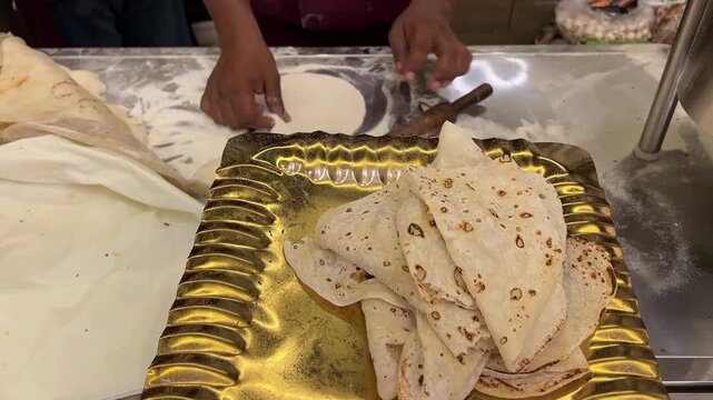 Indian chef preparing Rumali Roti at a live counter; a professional cook stretching traditional handkerchief bread during a wedding celebration in Kolkata, West Bengal.