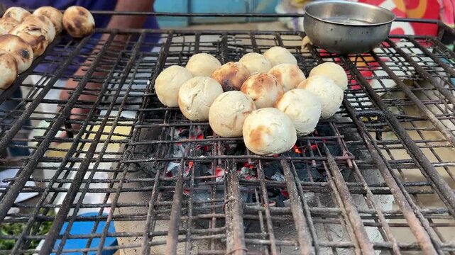 Litti Chokha being cooked at a roadside stall in Kolkata; professional street food photography of a traditional Indian meal being prepared over charcoal in an urban market setting.