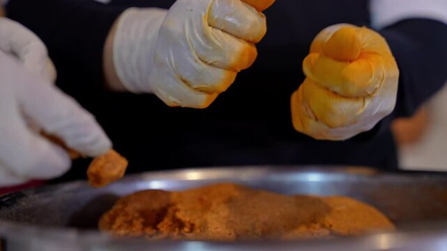 Close-up of gloved hands shaping kibbeh dough, forming traditional Middle Eastern stuffed bulgur balls, highlighting texture, technique, and hygienic food preparation process.