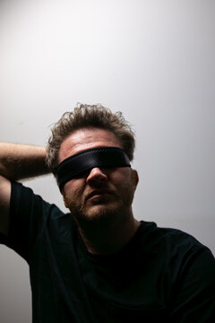 Blindfolded man in dramatic lighting symbolizing uncertainty and lack of awareness