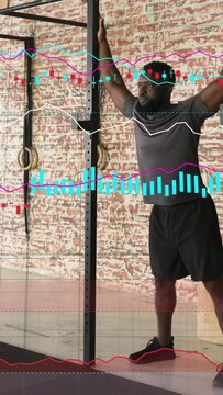 Vertical video: Man raising arms on fitness rig causing waveform chart HUD while prepping toe reach