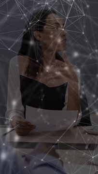 Vertical video: Woman reading sheet and leading business, animated network overlaying faces, table