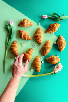 Hand Reaching for a Croissant on Brightly Colored backdrop