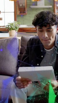 Vertical video: Man entering holding parcel sitting sofa opening document reading with tech overlay