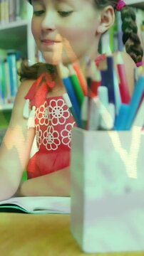 Vertical video: Child in red dress writing in notebook after teacher prompt in library