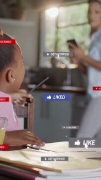 Vertical video: Kid sitting in kitchen drawing as mom checking phone sending social badges on table