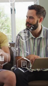 Vertical video: Man after friend prompt tapping tablet under floating hex icons, checking finance
