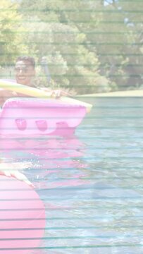 Vertical video: Man in shades lifting noodle moving float across pool leisure green tint overlay