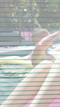 Vertical video: Man on pink ring reaching noodle, turning, then paddling left, creating lifestyle